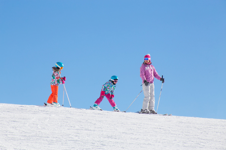 young woman skiing with two children at a ski resortの写真素材