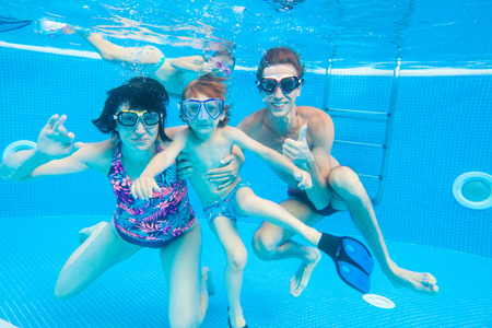 underwater photo of  little boy with his family  swimming  in poolの写真素材