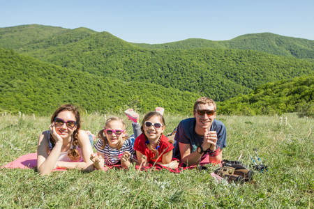 Family with two children resting on a meadow in a hike through mountainsの写真素材