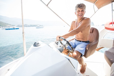 young man is driving a beautiful yacht on the steering bridge in the seaの写真素材