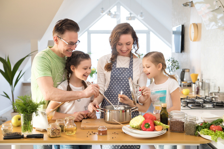 Family with young children cooking together in the kitchen at homeの写真素材