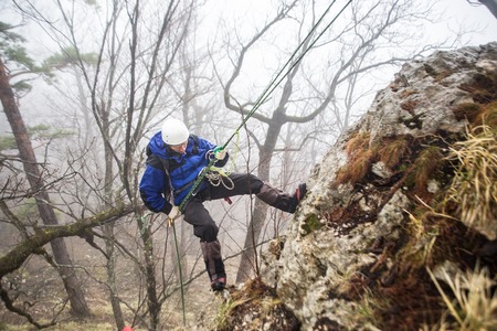 Climber in equipment and a helmet descends alone on a rope from a mountainの写真素材