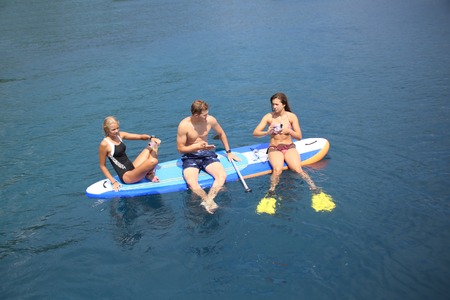 young people in swimming suit riding  on sup surfing in the seaの写真素材