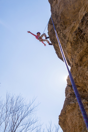 Little girl climbing on  rock in mountainsの写真素材