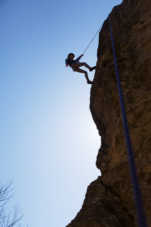 Little girl climbing on  rock in mountainsの写真素材