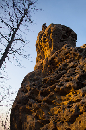 Climber in equipment and a helmet descends alone on a rope from a mountainの写真素材