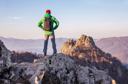 Young man climber stays  on top of mountainの写真素材