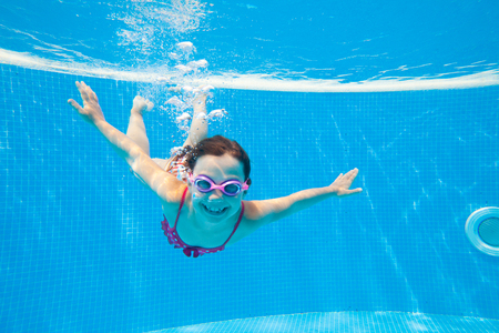 little girl deftly swim underwater in poolの写真素材