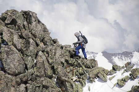 mountaineer with ice ax climbs on the mountain in the background of the landscape of snowy mountains