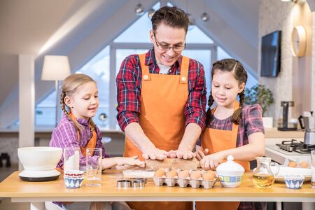 Father with little  children have cooking together in the kitchen at homeの写真素材