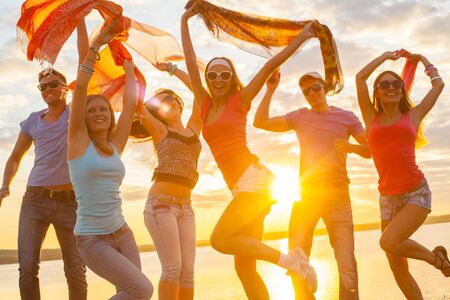 group of happy young people dancing at the beach on  beautiful summer sunsetの写真素材