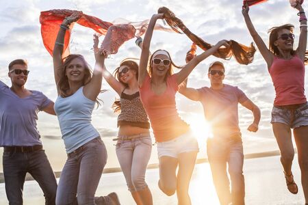 group of happy young people dancing at the beach on  beautiful summer sunsetの写真素材