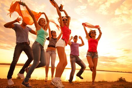 group of happy young people dancing at the beach on  beautiful summer sunsetの写真素材