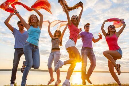 group of happy young people dancing at the beach on  beautiful summer sunsetの写真素材