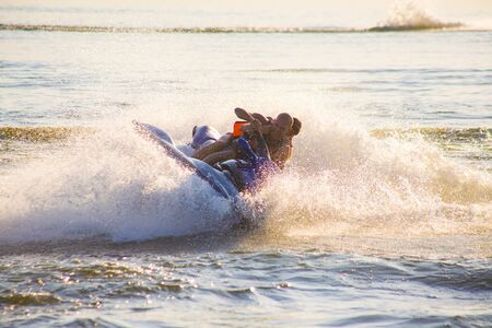 young man and woman drive on the jetski above the water at sunset .silhouette. spray.の写真素材