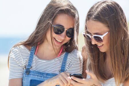 two girlfriends  teenagers spending time together with gadgetsの写真素材