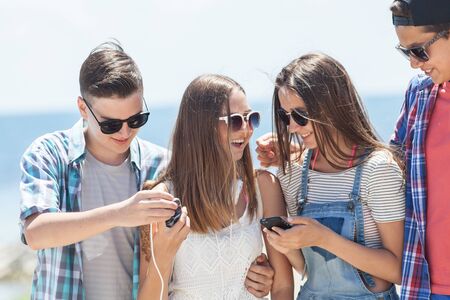 group of teenagers spending time together with gadgets