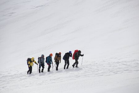 group of mountaineers with backpacks goes along the snowy slope of the mountainの写真素材