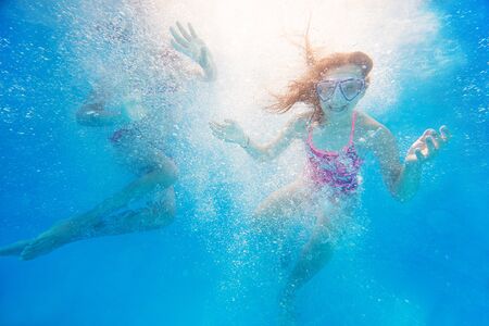 two little girls swimming  in pool  underwater.の写真素材