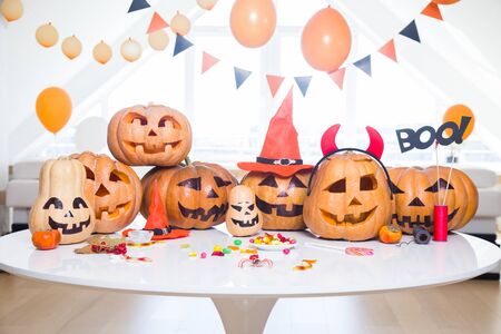 lot of pumpkins with painted faces on a table in a bright apartmentの写真素材