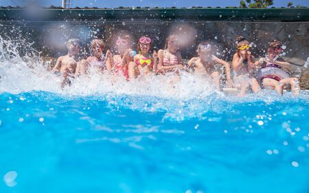 Children play fun with splashes on the side of the pool at the resortの写真素材