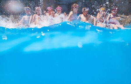 Children play fun with splashes on the side of the pool at the resortの写真素材