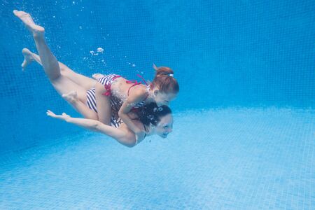 underwater photo of young mother with little girl in swimming  poolの写真素材
