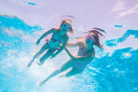 underwater photo of young mother with little girl in swimming  poolの写真素材