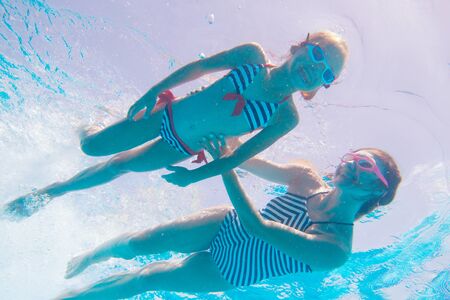 underwater photo of young mother with little girl in swimming  poolの写真素材