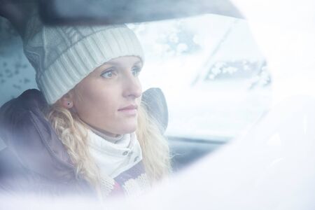 blonde young woman drives  in her  car in wintertimeの写真素材