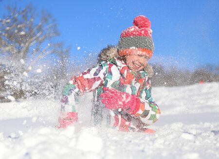 little girl playing on snow in winter timeの写真素材