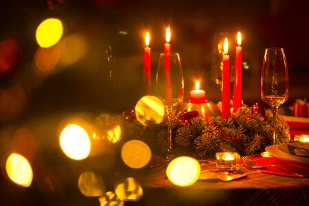 beautifully decorated Christmas table with candles and glasses near the Christmas treeの写真素材