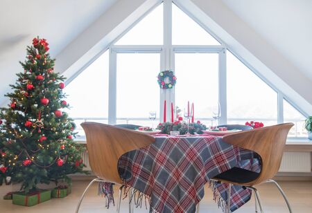 beautifully decorated Christmas table with candles and glasses near the Christmas treeの写真素材