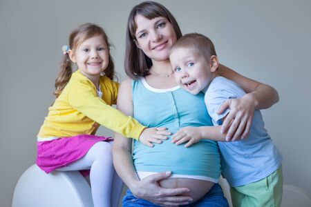 Portrait of happy pregnant woman with her two children togetherの写真素材