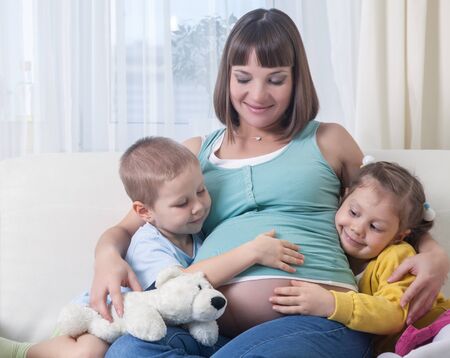 Portrait of happy pregnant woman with her two children togetherの写真素材
