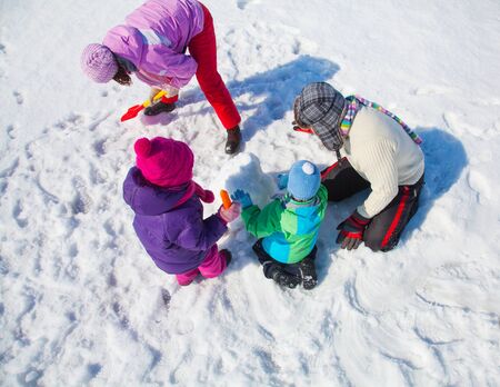 Happy couple with two children making big snowman