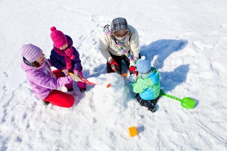 Happy couple with two children making big snowmanの写真素材