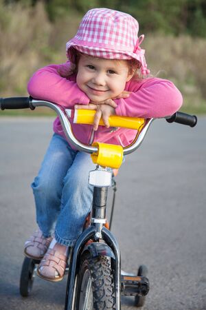 little cute girl rides a bicycle in  the street in summertimeの写真素材