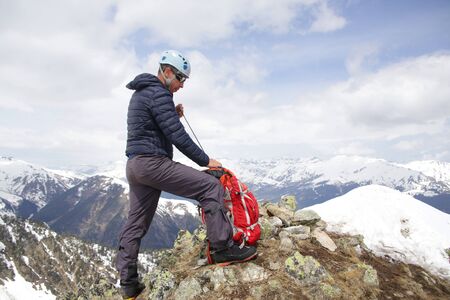 mountaineer with ice ax stands on the top of a mountain in the background of the landscape of snowy mountainsの写真素材