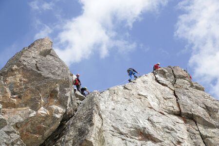 group of climbers climb a high rock in the mountainsの写真素材