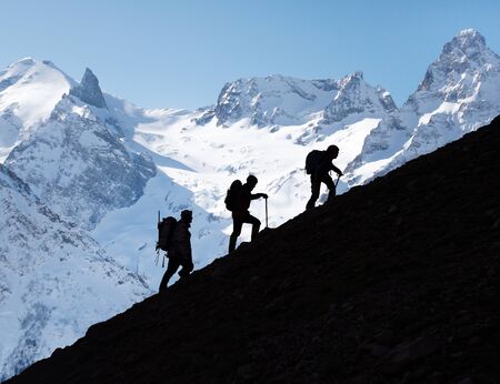  group of mountaineers with backpacks goes along the snowy slope of the mountainの写真素材