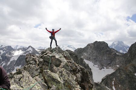 mountaineer with ice ax stands on the top of a mountain in the background of the landscape of snowy mountainsの写真素材