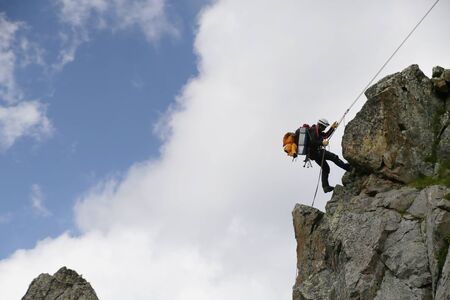mountaineer  descends from the mountain in the background of the landscape of snowy mountainsの写真素材