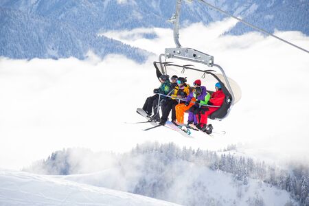 sports people on the chairlift in a ski resort among snow-capped mountains