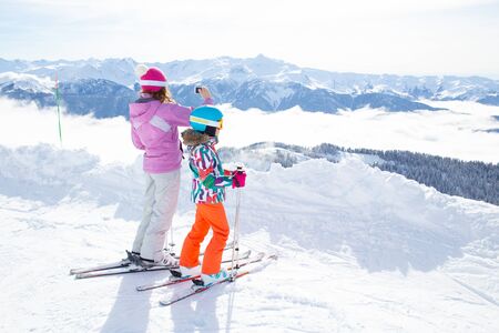 mom with her little daughter skiing at a mountain resortの写真素材