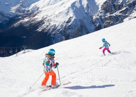 little girls on alpine skiing skating on slope in ski resortの写真素材