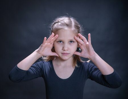 little girl looking through her arms directly at youの写真素材