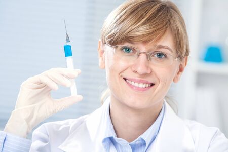 Portrait of female doctor smiling with syringe in hand in hospitalの写真素材
