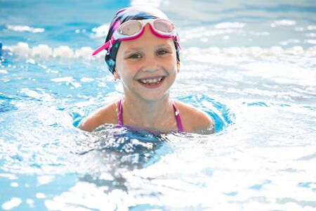 little girl swimming in the pool at the training in swimmingの写真素材