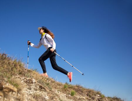 young woman runs in the mountains with sticks. Sky running,の写真素材